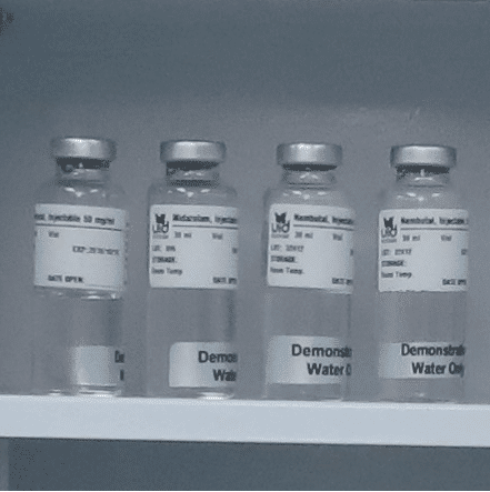 vial-w-labelpng - Unified Information Devices Four sealed glass vials with metal caps on a lab shelf; labels suggest they contain water or demonstration samples.